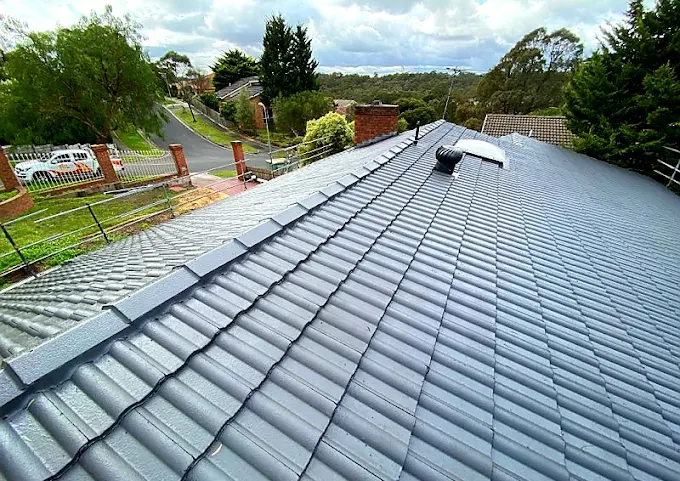 Freshly completed tile roof repairs showing resealed grey tiles and restored ridge capping on a residential home.